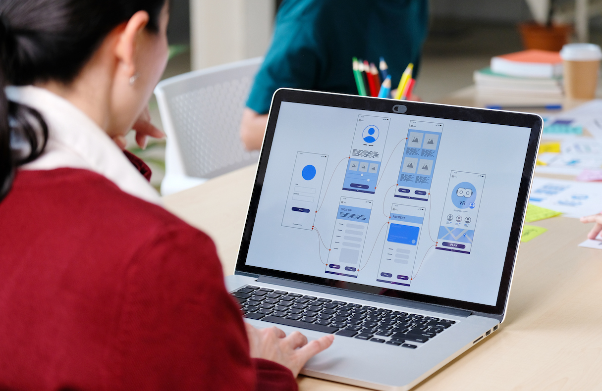 Woman working on laptop looking at UX/UI wireframe images