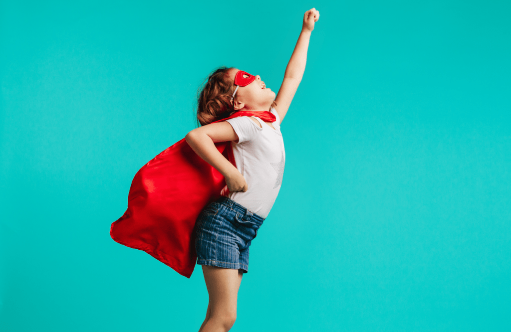 Girl dresses up as superhero with red cape and mask against blue background
