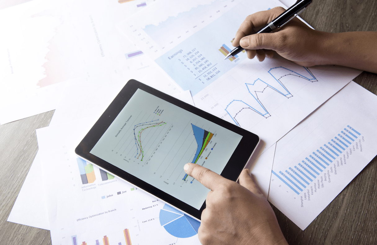 Person holding pen examining financial reports