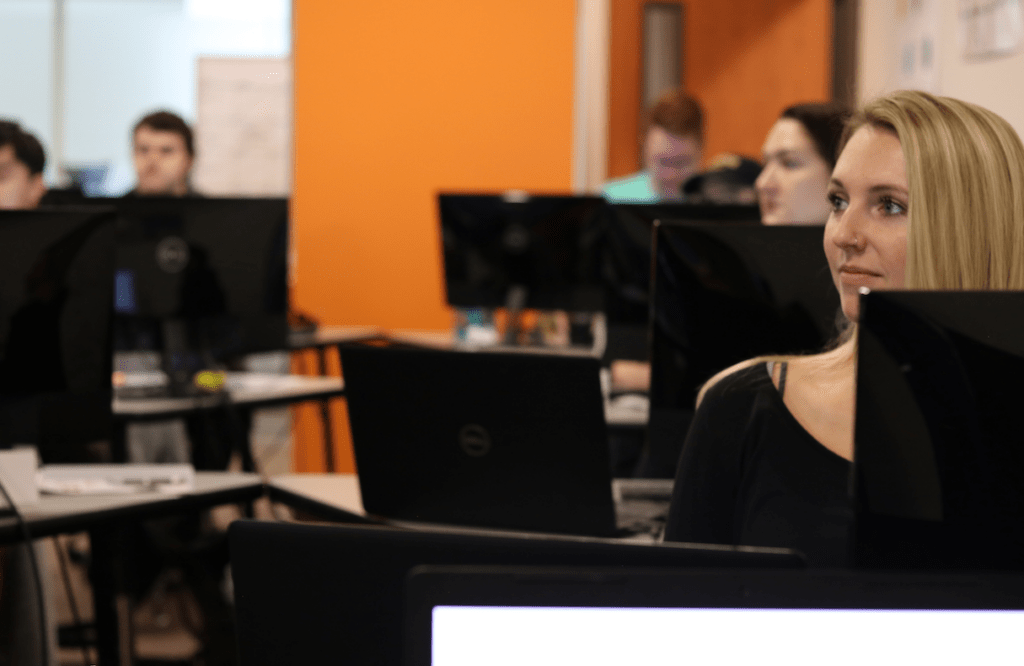 Woman with blonde hair sits at computer in Catalyte apprentice development program