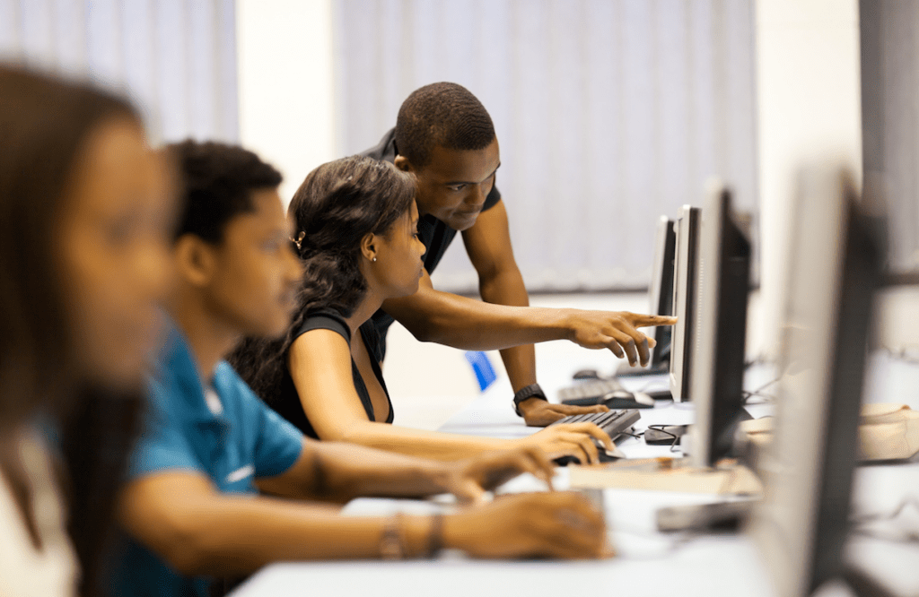 Man helps female student with work on a computer