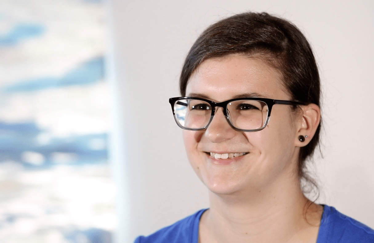 Woman with dark hair and glasses smiles at camera during a video interview