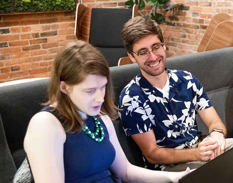 A man and a woman on a laptop computer solving a challenging software development problem.