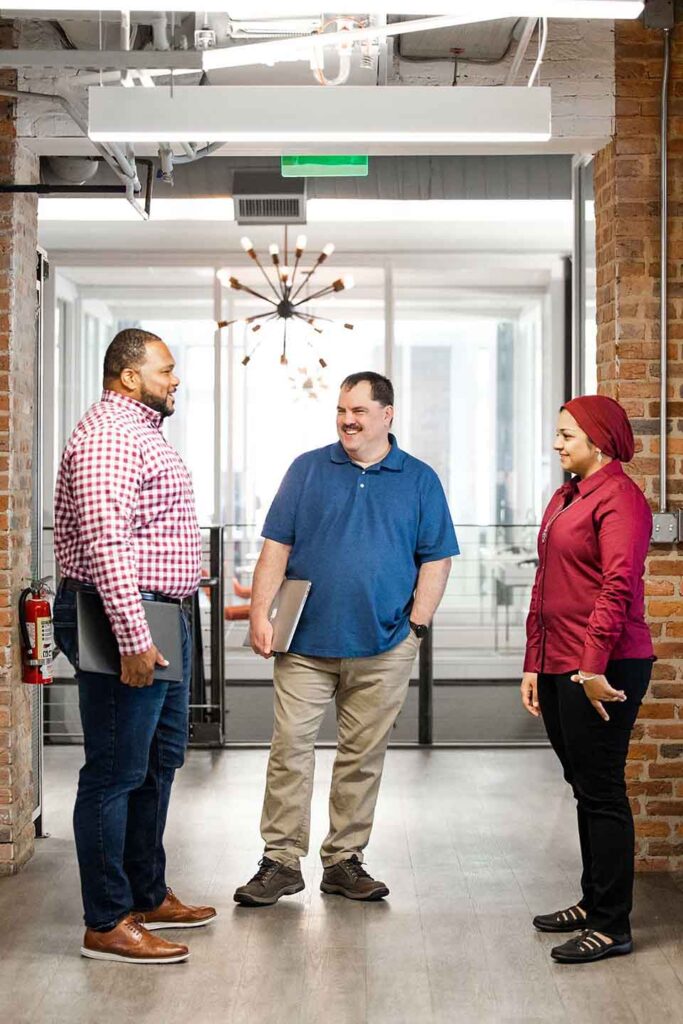 Three Catalyte employees, two men and a woman, standing and discussing client success.
