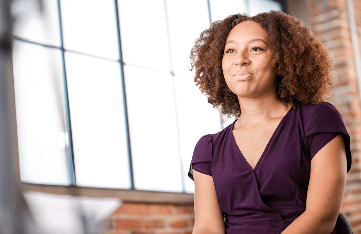 Women with curly brown hair and a purple shirt smiles into the camera