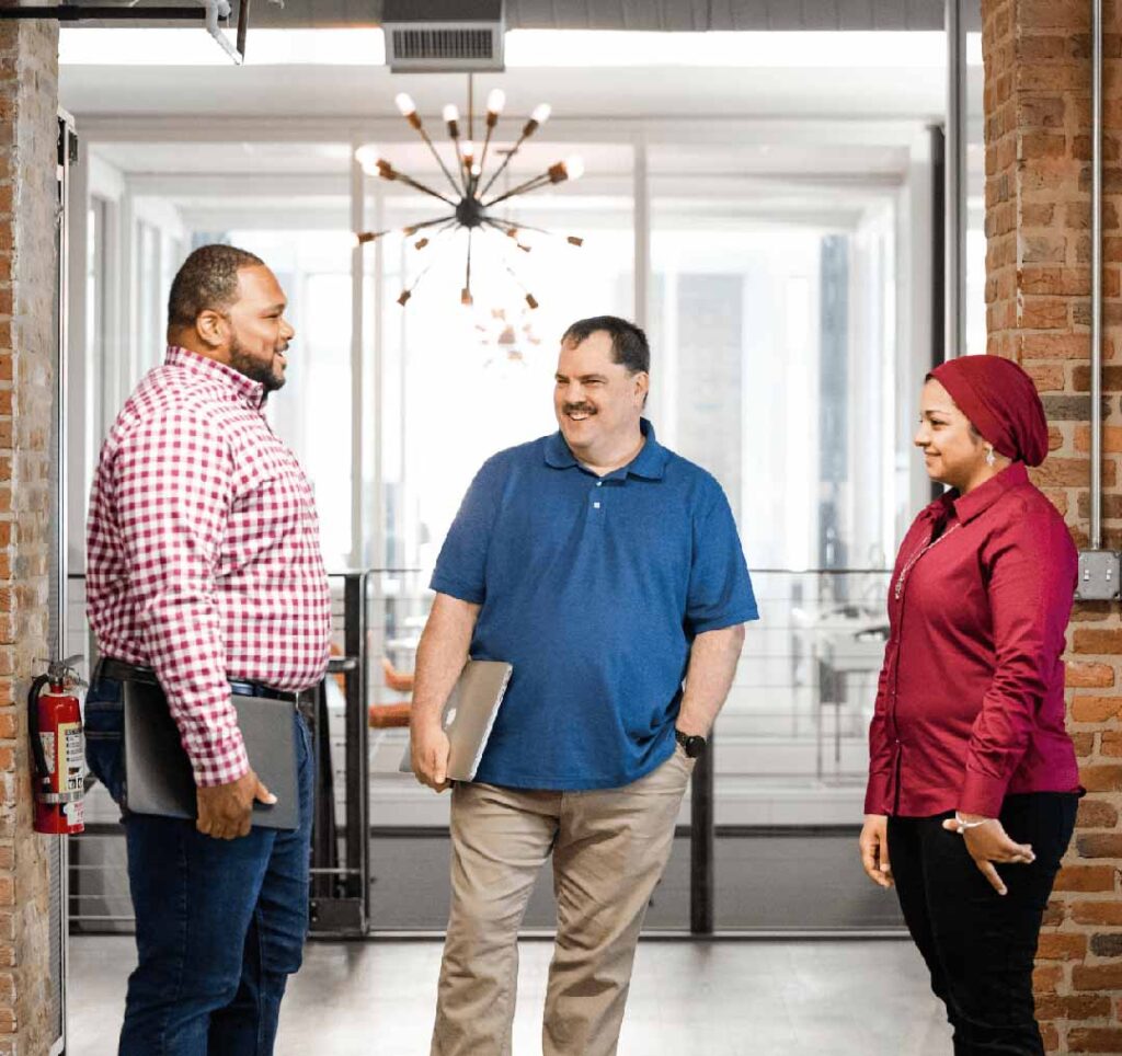 Three Catalyte employees, two men and a woman, standing and discussing client success.