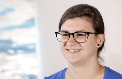 Woman with dark hair and glasses smiles at camera during a video interview