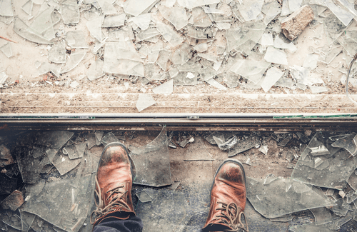 Boots standing next to pile of shattered glass