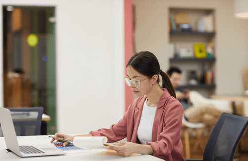 Woman with long ponytail sits working at a desk