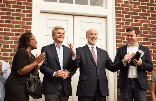 Group shot of four people standing in front of brick building