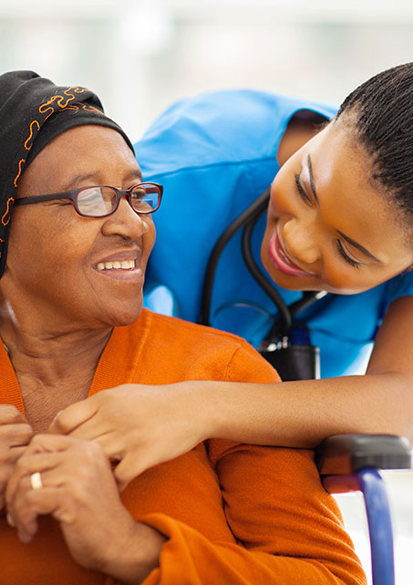 Nurse in blue scrubs comforts and older female patient.