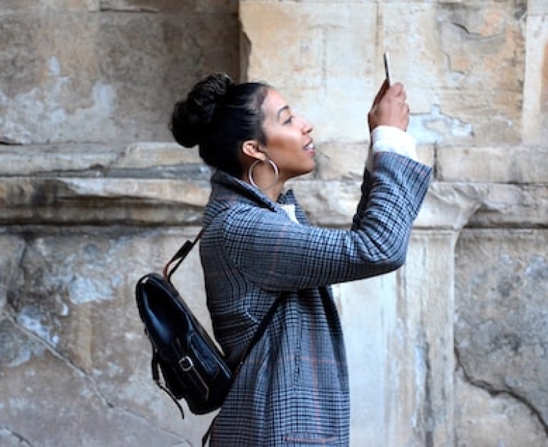 Woman with mini backpack take a photo with her phone