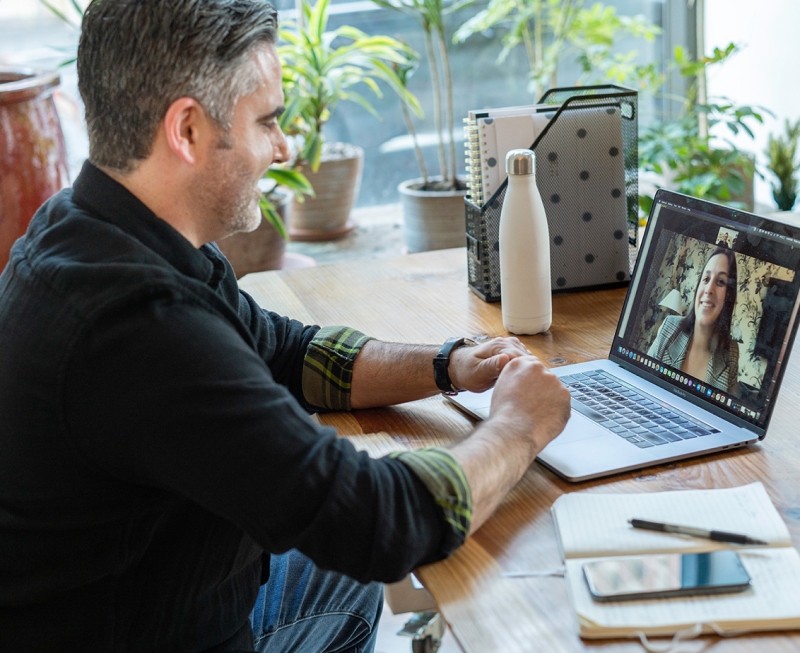Man in home office on video call with women