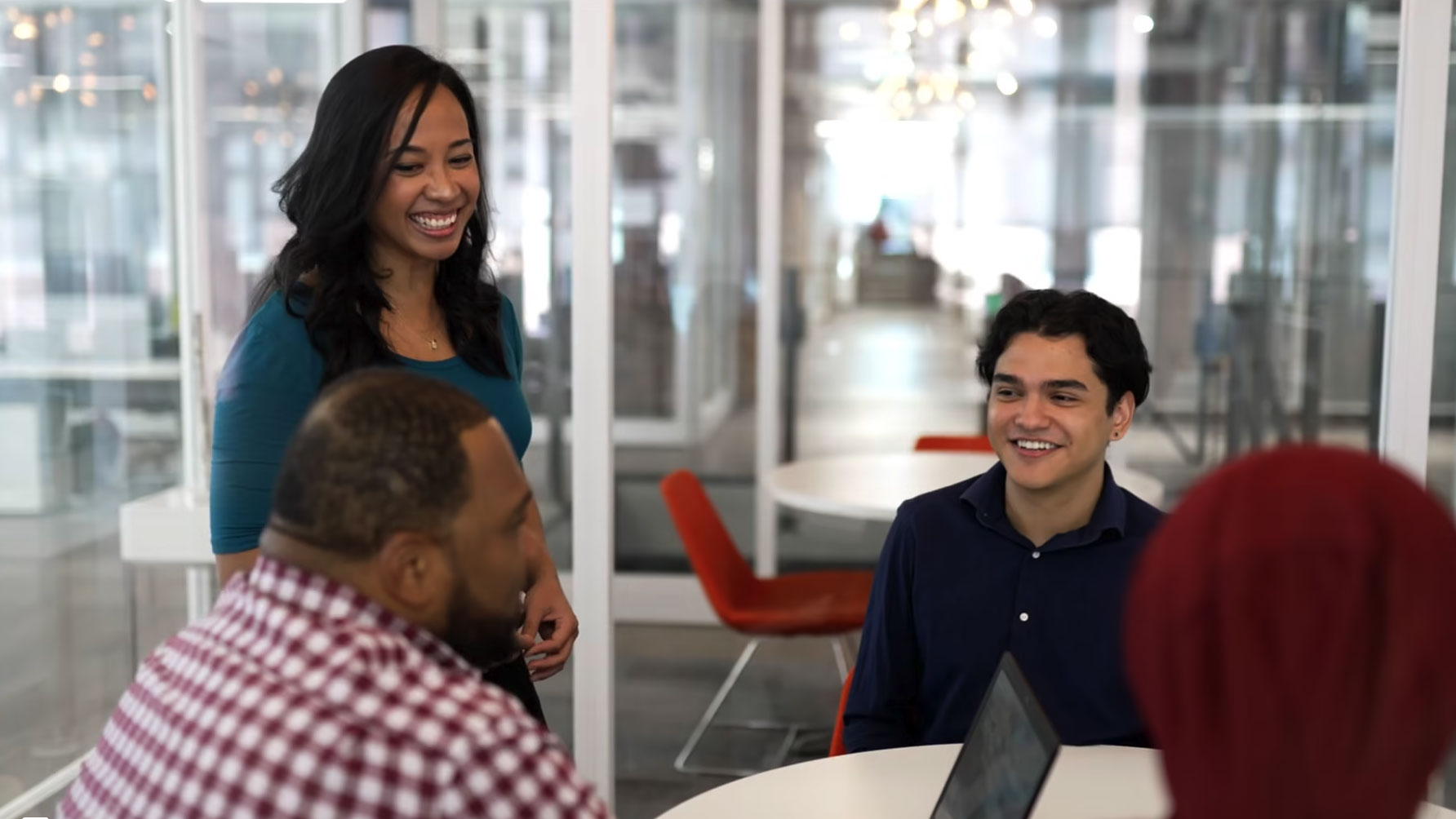 Three people, two men one women, hold a meeting in a small conference room