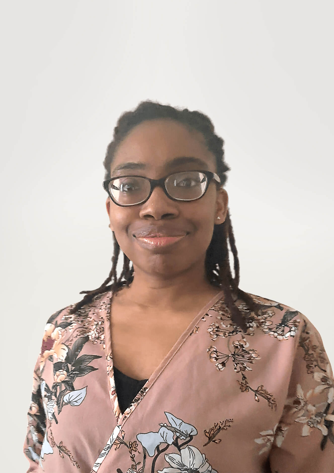 Woman with locs and glasses wearing a floral pattern shirt.