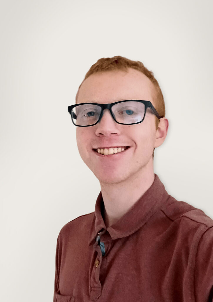 male with short hair, glasses and red polo shirt smiling at camera