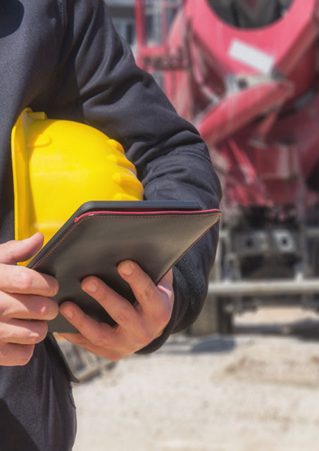 Person holding tablet with yellow construction helmet in the crook of their arm