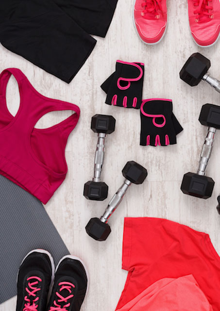 Athletic apparel and weights laid out on a grey floor.