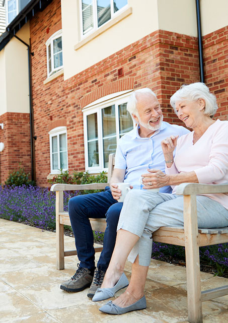 Two senior citizens sit on a bench