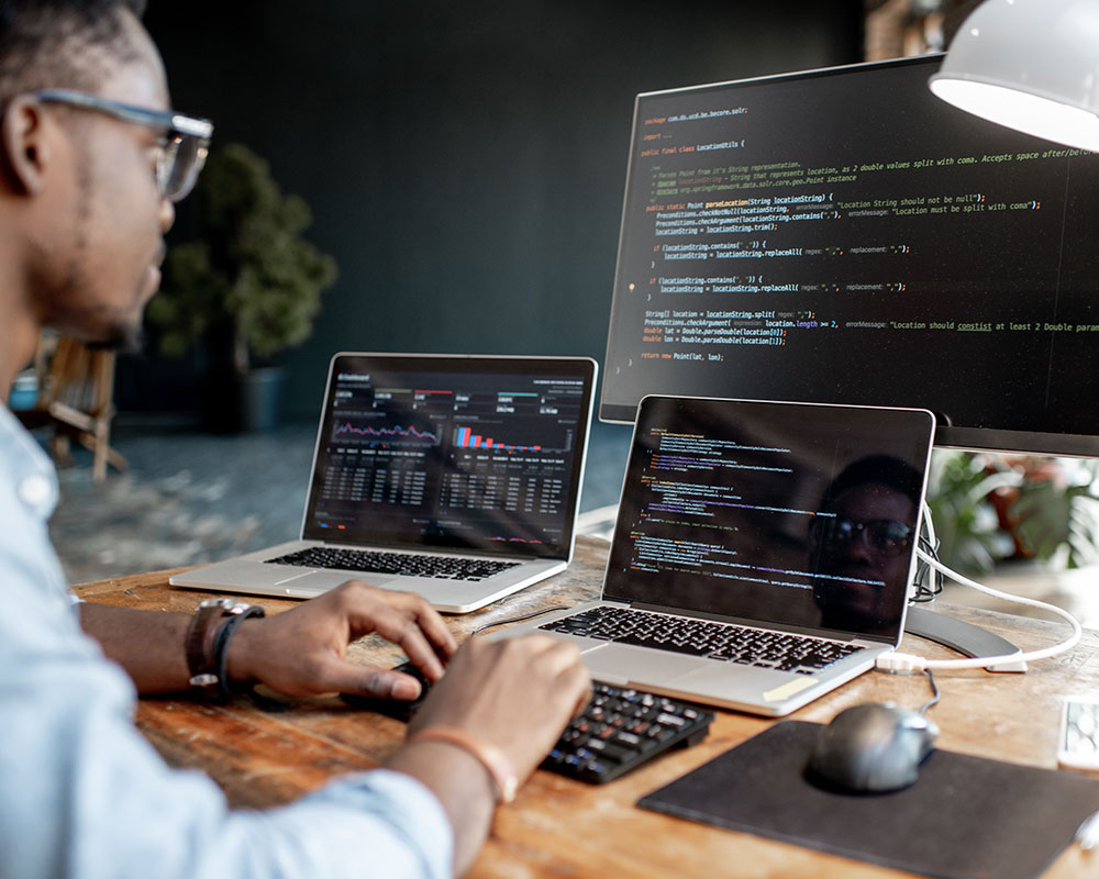 Man working in front of three computer screens