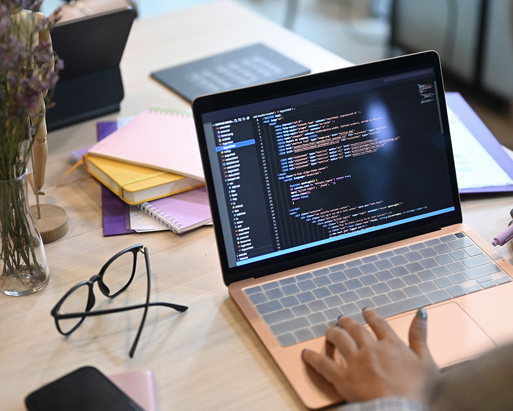 Laptop showing lines of code placed on a semi-messy office desk