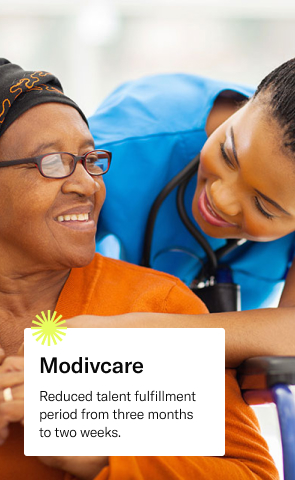 Nurse in blue scrubs comforts and older female patient. Text reads: Modivcare, reduced talent fulfillment period from three months to two weeks