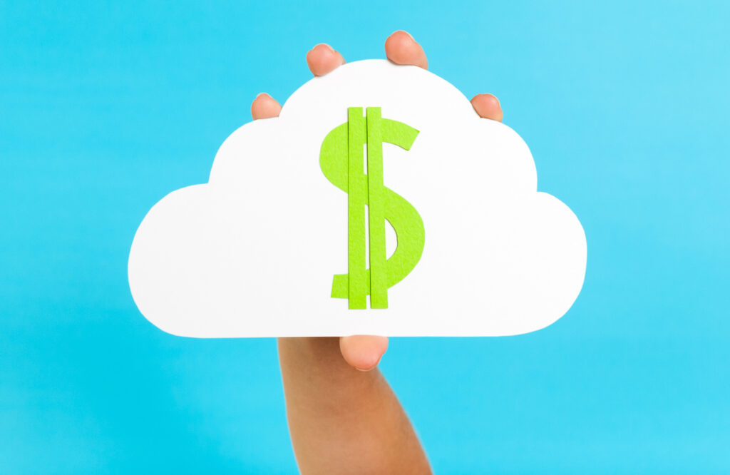 Hand holding a cutout of a white cloud with green dollar sign on the cloud against a blue back ground